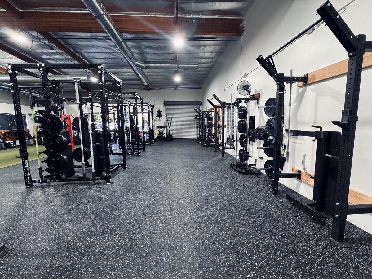 Open walkway between power racks and wall-mounted squat racks