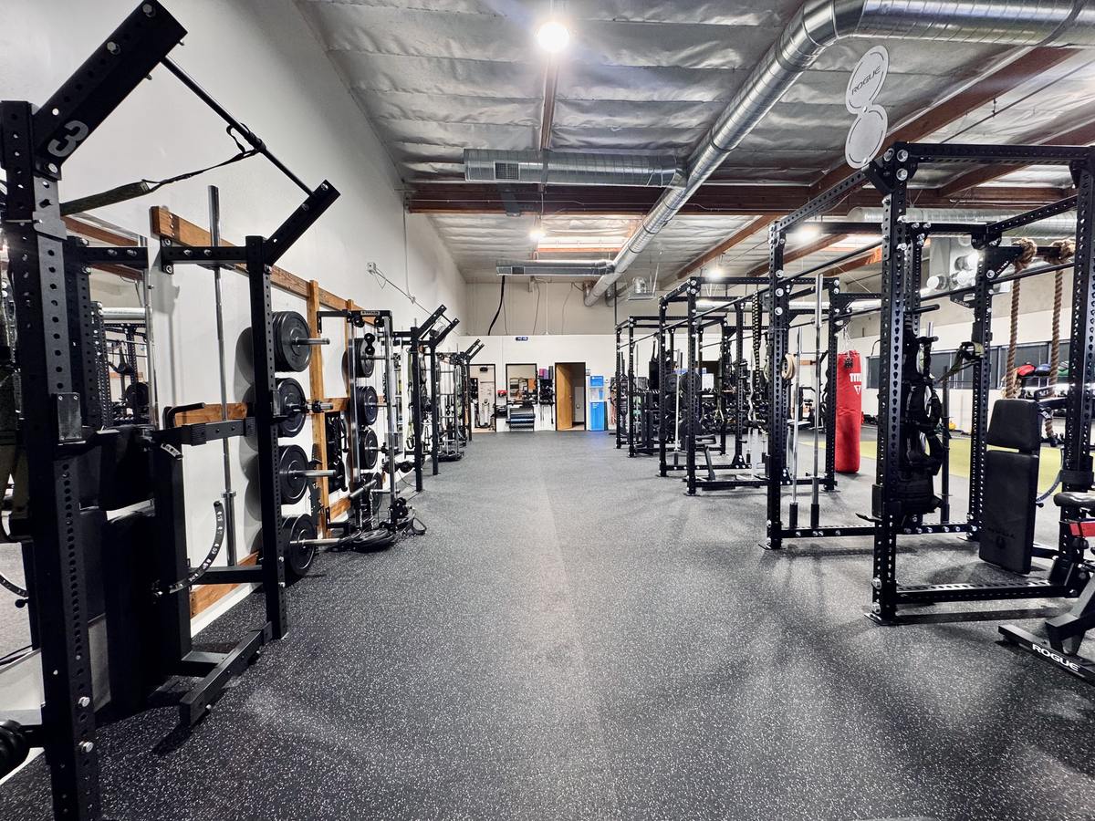 Open aisle between power racks and wall-mounted training stations